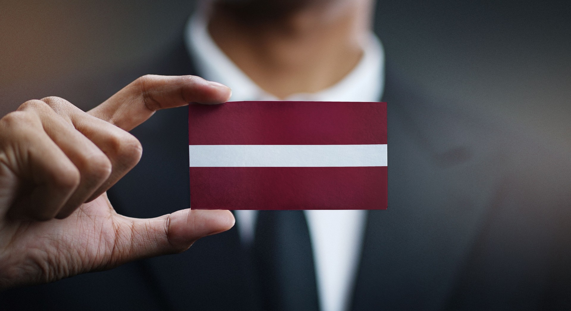 Businessman Holding Card of Latvia Flag